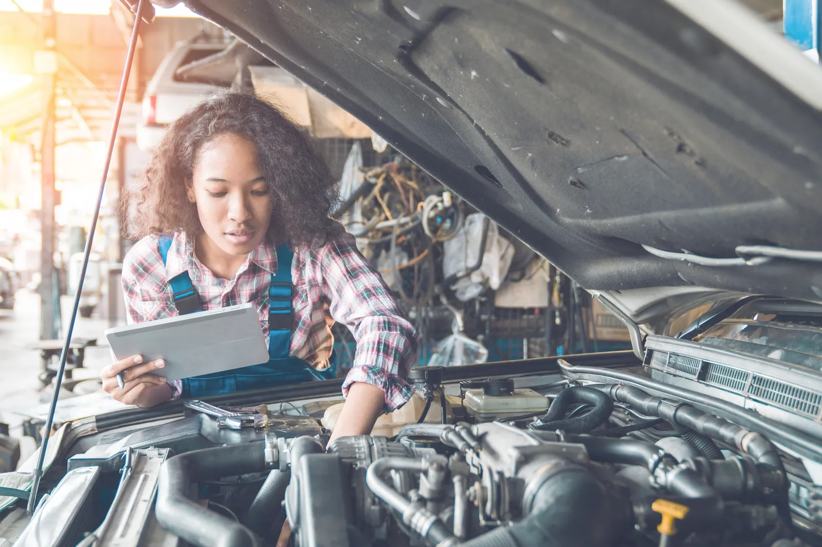 A mechanic checking an engine with a tablet